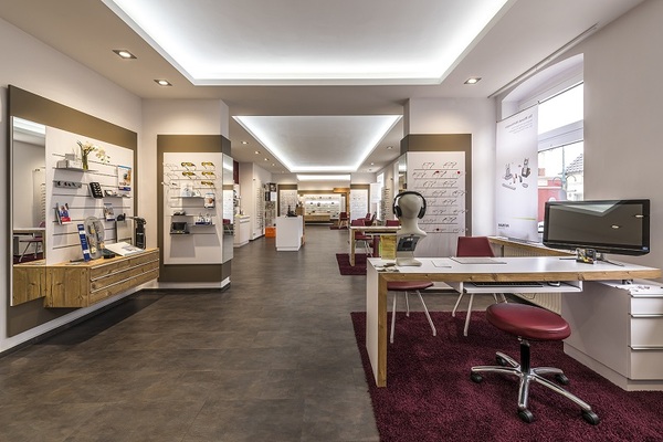 Modernes Optikergeschäft mit Beratungsbereich, Brillenausstellung und Computerarbeitsplatz.