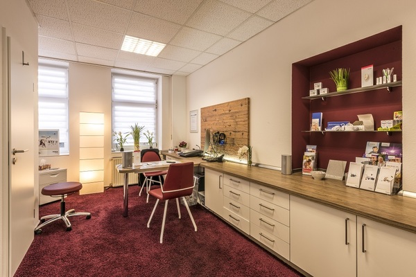 Modernes Beratungsbüro mit Schreibtisch, Regalen, Prospekten und gemütlicher Beleuchtung.